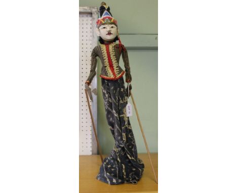 A carved and painted wood Indonesian puppet, fabric dressed, with stand base 57cm high