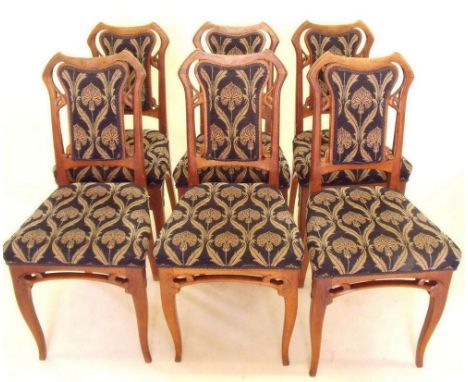 A set of six French Art Nouveau carved light wood dining chairs with sinuous supports to backs and legs, upholstered in styli