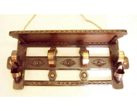 A Flemish early 20th century carved oak hall coat rack and hat shelf with applied copper decoration and clogs, 76cm wide