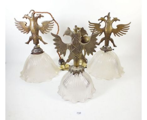 A pair of double headed eagle form brass light fittings with clear glass frilled shades and one other similar light fitting