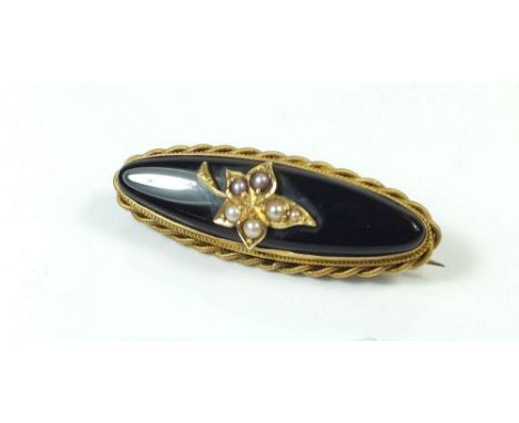 A Victorian black stone and gold oval mourning brooch with seed pearl set leaf motif and hair locket to reverse, 3.6cm long 