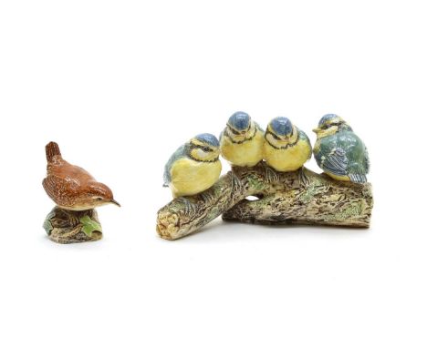 Two pottery bird models by Eva Soper, the first of four blue tits sitting on a log, 17cm long, the second of a wren, 7cm long