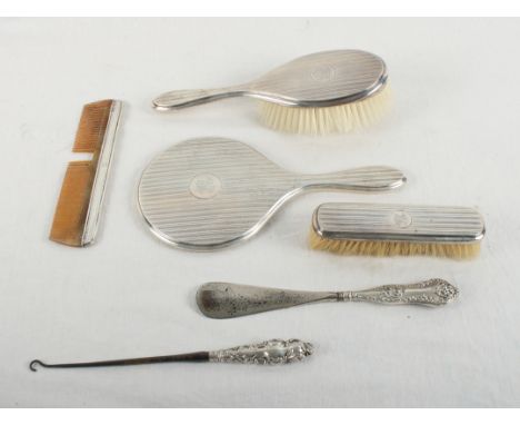 A silver dressing table set comprising a mirror, two brushes, a comb, a shoehorn and a button hook