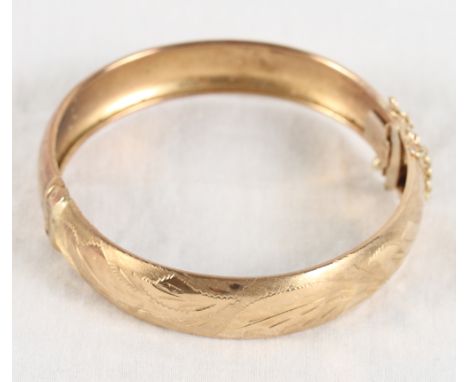 A 9ct gold hinged bangle with engraved decoration, 14.9g