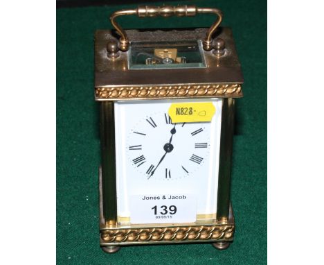 A carriage clock in gilt metal case decorated curb link chain bands, plain white enamel dial, 6 1/2" high
