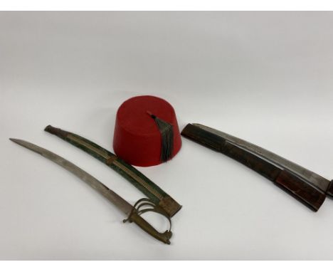 A red cloth Fez hat and two Eastern swords, the largest measures 60cm L