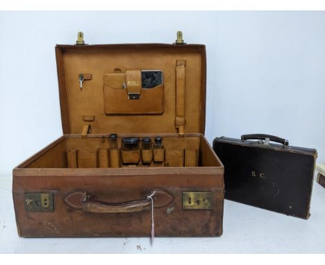 A vintage leather travelling case with four silver topped glass bottles, London 1911, and other items to fitted interior, alo