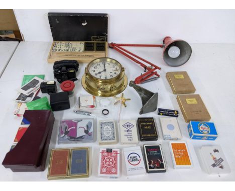 A mixed lot to include a collection of playing cards, a brass German wall clock, an industrial angle poise wall lamp, photogr