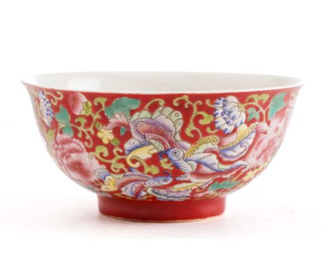 A Chinese porcelain bowl, painted with butterflies amongst flower and leafy tendrils against a red ground, apocryphal four ch