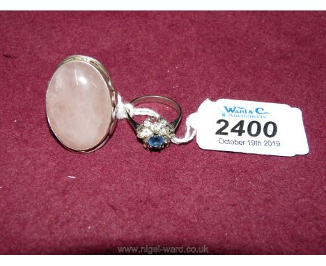 An unhallmarked white metal ring set with an oval pink rose quartz stone, ring size "O", and a silver metal cluster ring mark