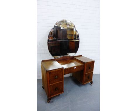 An Art Deco burr walnut dressing table, the mirrored back over central drawer flanked by two deep drawers to each pedestal on