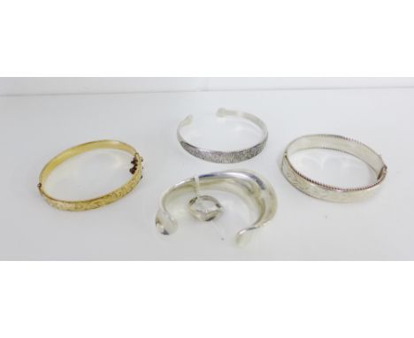 A collection of bangles and cuff bracelets to include a Birmingham silver engraved bangle, a gold plated bangle, an Eastern w