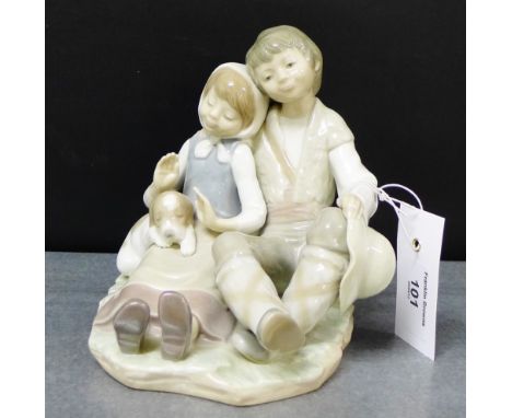 A Lladro porcelain figure group of a boy and a girl with a puppy dog, modelled seated, 16cm high
