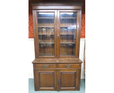 A Victorian oak glazed bookcase with moulded cornice over pair of glazed doors over two drawers over two panel cabinet doors,