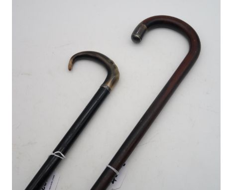 An ebonised walking stick with curved horn handle and narrow band stamped "Silver"; and another walking stick with silver mou