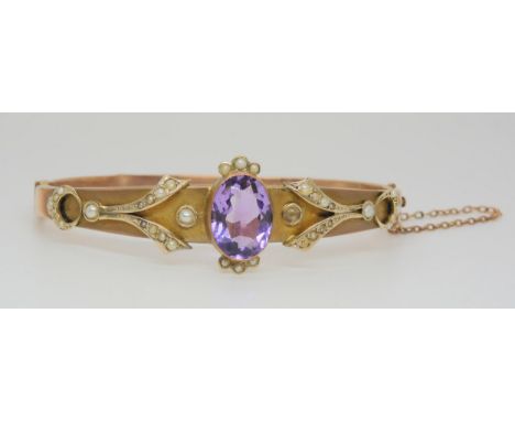 A Victorian 9ct rose gold bangle, with central set amethyst surrounded by seed pearls, 9.1gms Condition Report:Available upon