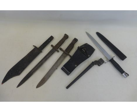 A clean example of a Swiss bayonet in its scabbard, a British spike bayonet, two other bayonets and a machete blade.