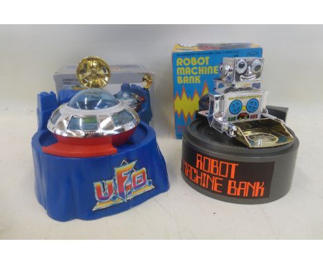 A boxed robot machine bank, made in Hong Kong and a boxed UFO saving bank (also made in Hong Kong).