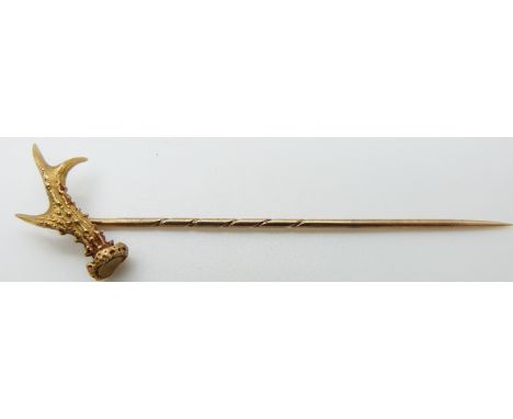 A yellow metal stick pin in the form of an antler with textured detail