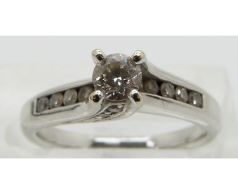 An 18ct white gold ring set with a round cut diamond of approximately 0.25ct with diamond encrusted shoulders, size K