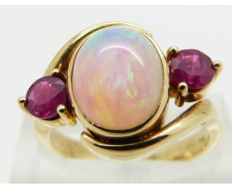 An 18ct gold ring set with an oval opal cabochon and two round cut rubies, size M