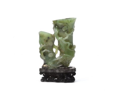 An unusual Chinese pale spinach green jade 'pine and prunus' vase, Qing dynasty, 18th century, naturalistically hollowed as t