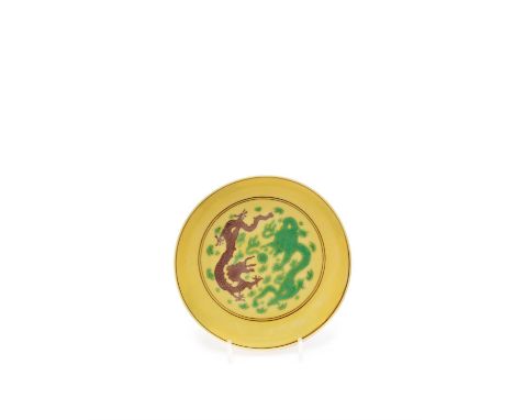 A Chinese imperial porcelain saucer dish, mark of Kangxi and of the period (1662-1722), painted on a yellow ground and incise
