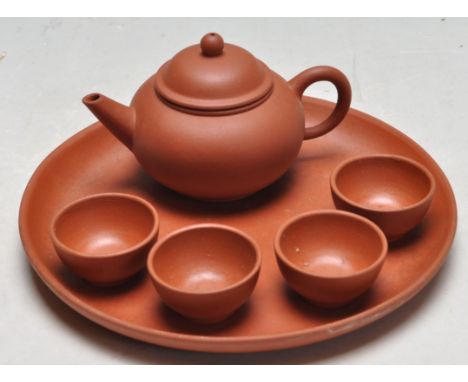 A vintage 20th century Chinese red clay Yixing Zisha tea pot of small form having a tray with four small bowls. Makers seal m