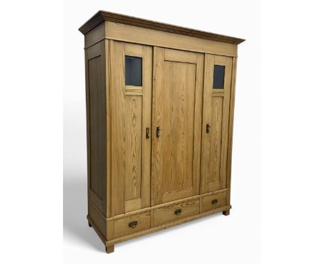 Early 20th century Continental stripped pine triple wardrobe, projecting moulded cornice over three panelled doors with glass