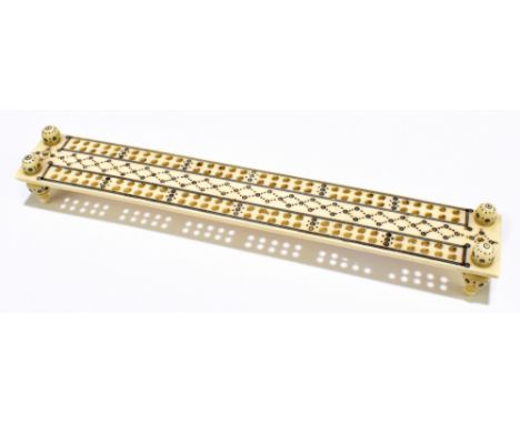 An early 20th century Indian carved ivory Vizagapatam-type cribbage board with penwork decoration and raised on four turned s