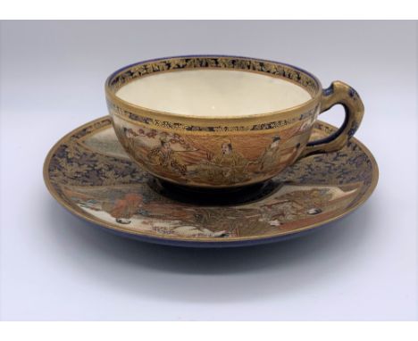 KINKOZAN; a Japanese Meiji period Satsuma cup and saucer decorated with panels of seated figures within a cobalt blue ground,