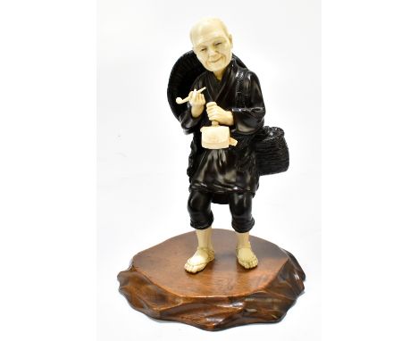 A Japanese Meiji period bronze and ivory okimono of a standing elder holding a pipe, raised on a wooden plinth base, height 1