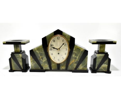 A French Art Deco black slate and onyx three piece clock garniture, the clock of shaped rectangular form with oval silvered d