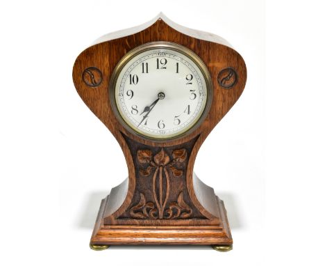 An Arts & Crafts oak balloon shaped mantel clock, the central enamel dial with Arabic numerals flanked by floral decoration r