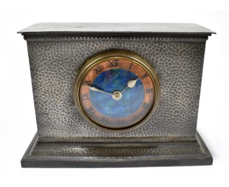 TUDRIC PEWTER FOR LIBERTY &amp; CO; a pewter mantel clock with planished decoration surrounding the blue enamel dial, impress
