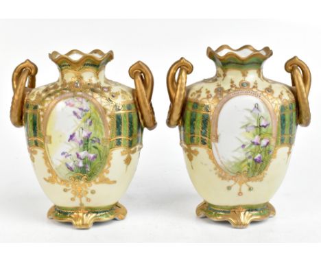 NORITAKE; a pair of twin handled hand painted vases, decorated with floral sprays inside jewelled decoration, height 21.5cm.A