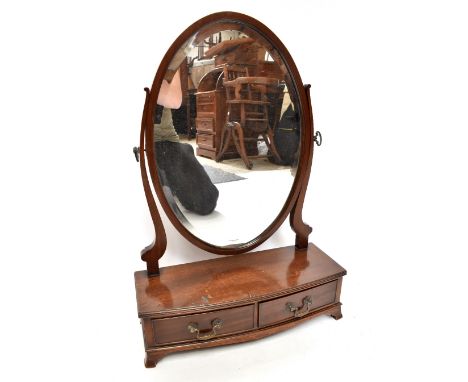 An early 20th century mahogany swing toilet mirror with oval bevelled plate above a bow fronted base set with two drawers and