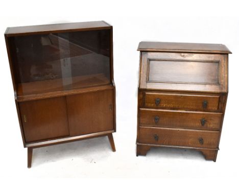 A 1970s oak bookcase, the upper section with glazed sliding doors enclosing an adjustable shelf, the base section with two pa