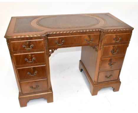 A mid-20th century kneehole mahogany desk, the top inset with tooled brown leather sections above one long and eight short dr