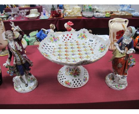 A Pair of Sitzendorf Figures, depicting a country lady and gentleman in period dress, each beside a tree stump encrusted with