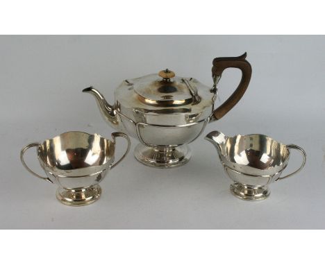 A George V silver three piece tea service
Comprising teapot with hardwood handle and lid finial, raised on circular spreading