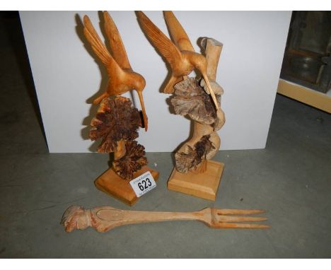 Two carved wood birds and a carved wood fork.