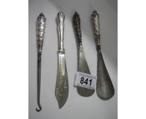 Three silver handled shoe horns and a button hook.