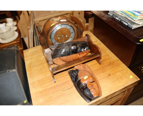 A mahogany cased mantel clock with 8 day movement; an oak book trough and two face masks 