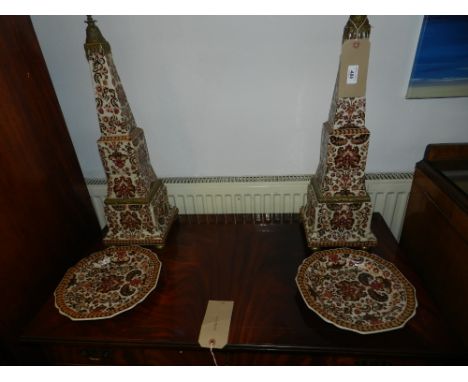 A pair of ceramic obelisks, having red floral decoration upon white ground, together with two matching plates.
