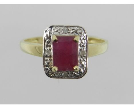 A yellow metal, diamond, and ruby set dress ring, the emerald cut central ruby surrounded by a white metal illusion set diamo