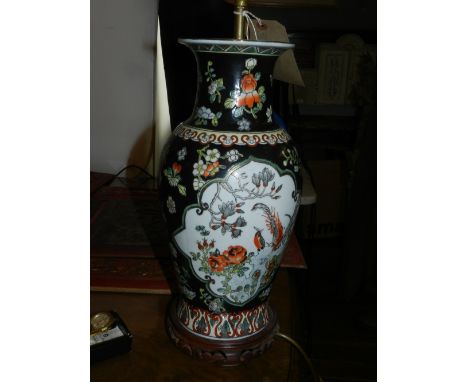 A Chinese famille noir porcelain table lamp base, of baluster form, decorated with vignettes to each side amongst flowers and