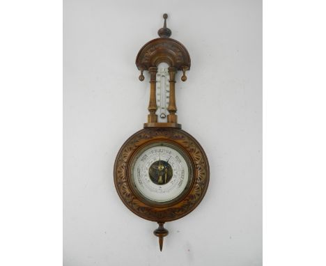 A late 19th century carved walnut aneroid wheel barometer, mounted mercurial thermometer. H: 46cm