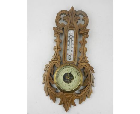 An early 20th century carved beechwood aneroid barometer, mounted mercurial thermometer. H: 40cm 