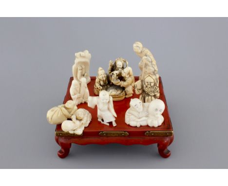 A set of 9 small Japanese ivory carvings, incl. netsuke, on a small red lacquer table, 19th/early 20th C. H.: 6,5 cm (the tal